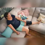 Compex ComfortTENS Knee põlvetugiside kasutamine diivanil puhates, juhtplokk reie peal
