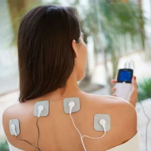 EM49 elektroodid naise õlgadel ja ülaseljal, seade käes stimulatsiooni ajal