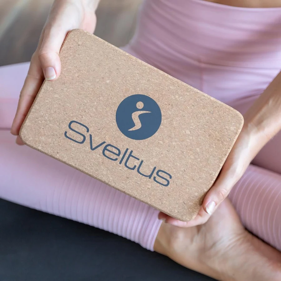 Sveltus korgist joogaploki pind ja logo lähivaates käte vahel